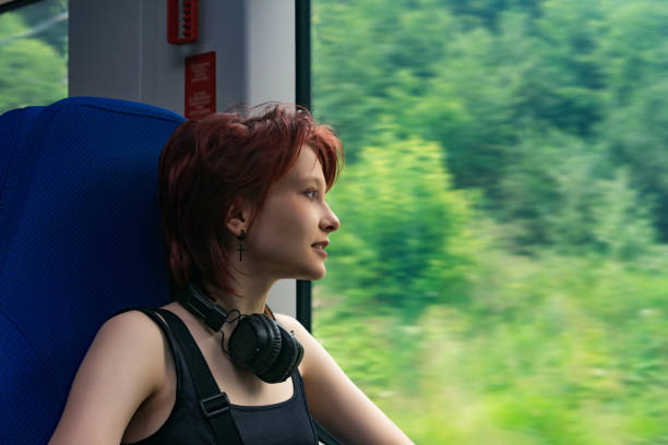dziewczyna jedzie pociągiem poza miastem i patrzy przez okno na naturalny krajobraz zamazany w ruchu - high speed train audio zdjęcia i obrazy z banku zdjęć