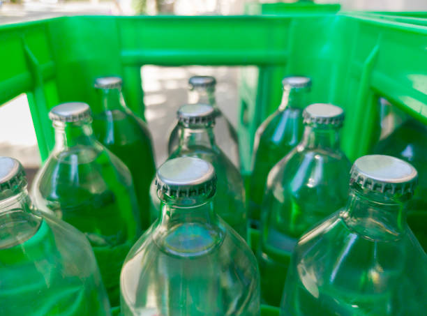 A closeup of the mouth of a green glass bottle on a white background