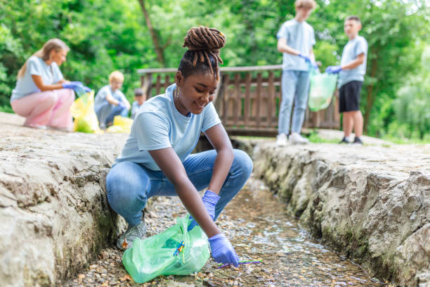 une femme ramasse à la main des ordures en plastique dans la rivière au parc. journée mondiale de l’environnement. concept d’environnement. - bag garbage bag plastic black photos et images de collection