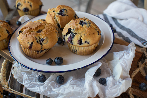 Delicious and fresh baked big blueberry muffins ready to eat on a rustic plate