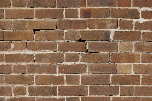 Background texture of a brown brick wall with white mortar.