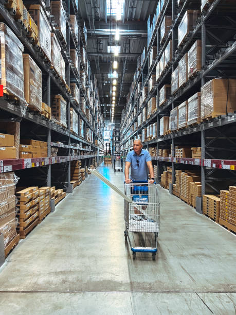Man in Big Box Store Shopping with Cart Mature man standing with trolley cart in huge distribution warehouse megastore stock pictures, royalty-free photos & images