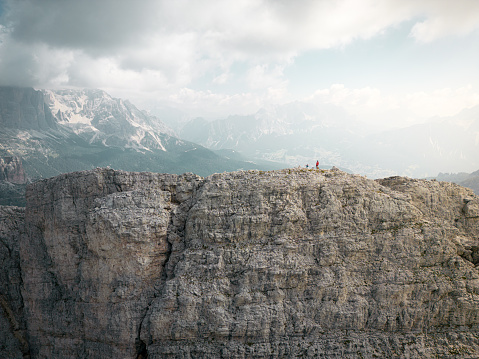 Alpine hikers on top of a rocky edge in cloudy weather in italien alps