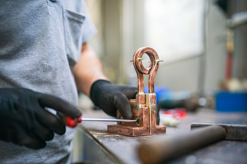 Red pipe cutter in the hands of the master during the repair or installation of gas equipment on the table in the workshop.