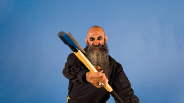 istock halloween themes | spooky threatening bearded man holding an axe with expression of anger while looking at camera 1414180730