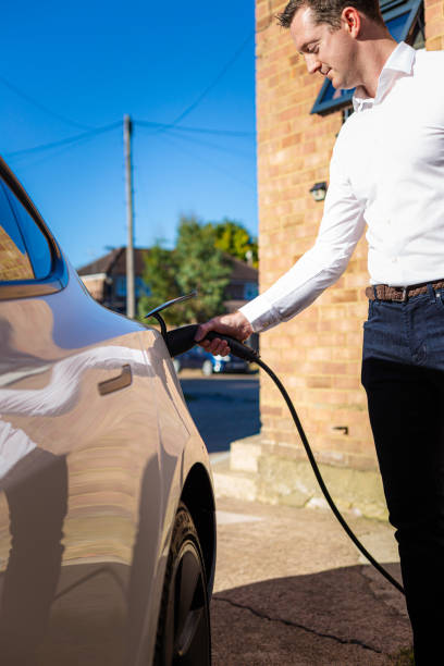 istock Man charging electric car at home 1414184255