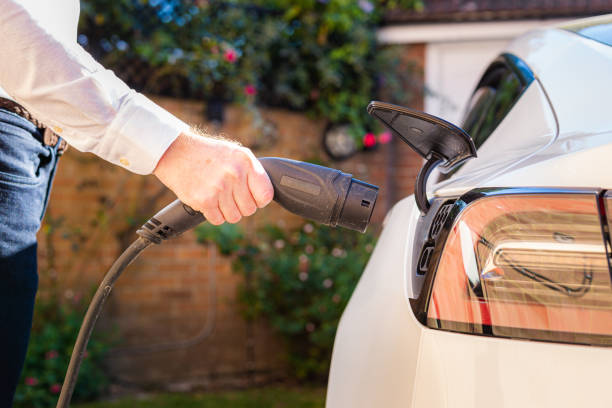 Man charging electric car at home stock photo