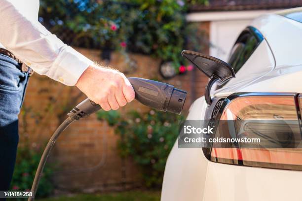 Man Charging Electric Car At Home Stock Photo - Download Image Now - Electric Vehicle, Electric Car, Domestic Life
