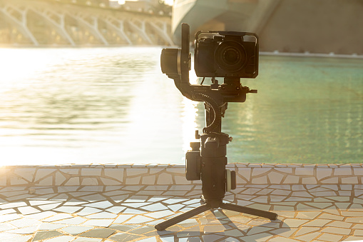 Gimbal with camera standing in front of the water. Concept videographer