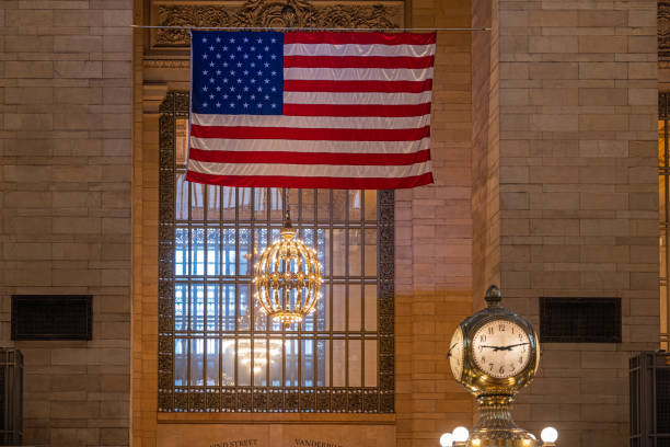Grand Central Station, Manhattan, New York, NY, USA - July 3 2022: American National flag, window, lamps and station clock in a quiet corner of the station