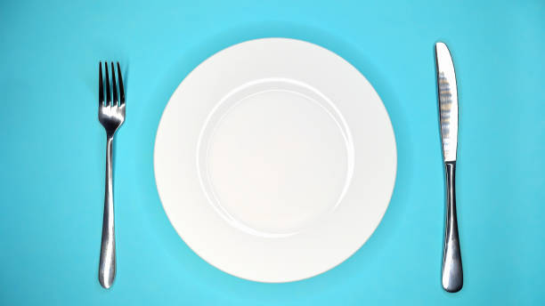 istock Table setting in restaurant or cafe. Fork and knife. White plate on blue table 1414205295
