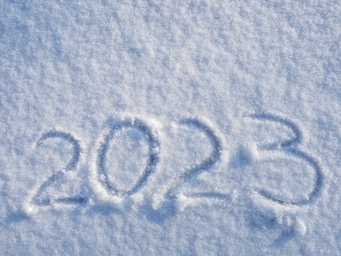 top view on 2023 hand written on the snow. 2022 new year holiday text drawn on snow. 2022 year hand written in snow