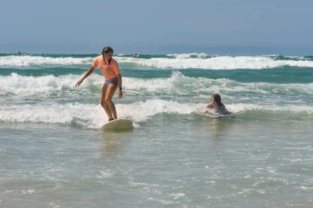 istock Two sisters surfing together in the waves in summer 1414216518