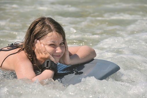Pretty girl bodyboarding in the waves in summer
