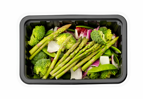 Broccoli asparagus onion in a plastic tray isolated on white.