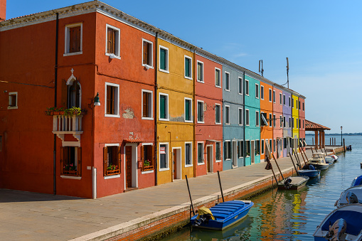 Burano island, Venice, Veneto, Italy. July 25 2022. Editorial stock picture of the streets, alleys and very colorful small houses on the small island of Burano, Venice, Italy. Burano is known for its lace and these multi colored houses. It is a beautiful sunny summer day, that makes the house colors pop.