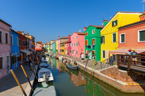 Burano island, Venice, Veneto, Italy. July 25 2022. Editorial stock picture of the streets, alleys and very colorful small houses on the small island of Burano, Venice, Italy. Burano is known for its lace and these multi colored houses. It is a beautiful sunny summer day, that makes the house colors pop.