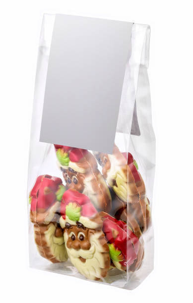 A close-up image of colorful festive sweets shaped like snowmen, encased in layers of plastic foil wrap. The focus highlights the excessive use of packaging materials, drawing attention to broader themes of pollution, waste, and environmental concerns related to modern consumer habits.