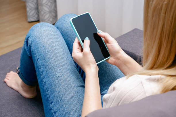 istock A woman at home sitting on the couch communicates with relatives via video call using a smartphone. Young woman making video call with her family 1414219339