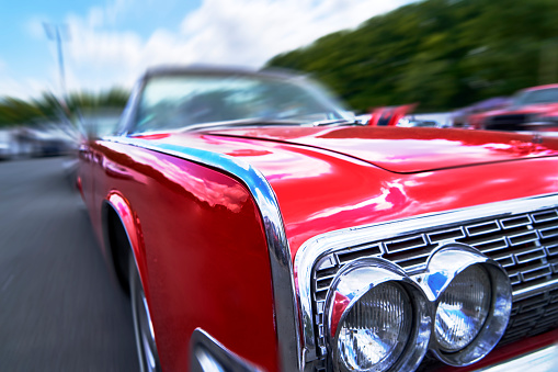 Front corner of red American road cruiser with the headlights and abstract background in zoom blur