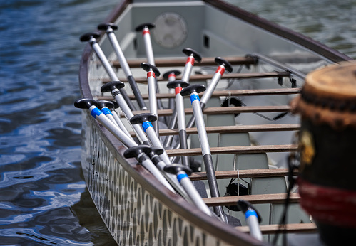 Paddles on the rows of seats of an empty dragon boat before the start of the competition on the water, selective focus,