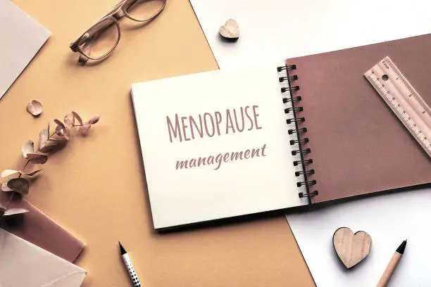 Photo of Caption motivator text Menopause management in square album, notebook with spiral binder. Monochromatic beige color hues.