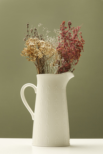 Ceramic jug with bunch of various dried flowers and plants
