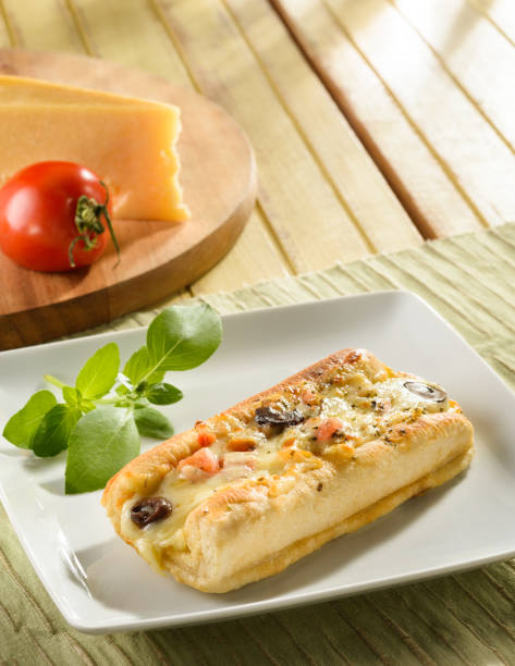fresh ciabatta bread with cheese, tomato and basil filling on a plate, on a fabric placemat, with wooden table background - lanche da tarde imagens e fotografias de stock