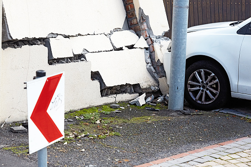 The damaged front of a car and a cracked, leaning suburban boundary wall in the immediate aftermath of a collision in the southern suburbs of Cape Town, South Africa.