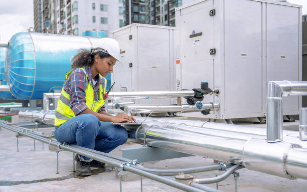 大型工場空調機の冷却システムを女性エンジニアが点検・制御。 - air duct air conditioner pipe pipeline ストックフォトと画像