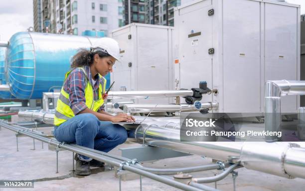 Female Engineer Inspects And Controls The Cooling System Of A Large Factory Air Conditioner Stock Photo - Download Image Now