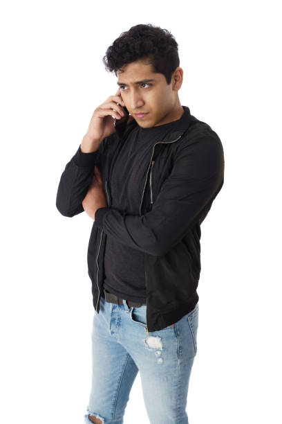 A happy young latin men standing with hand in pocket, talking on a mobile phone and looking away with a smile.