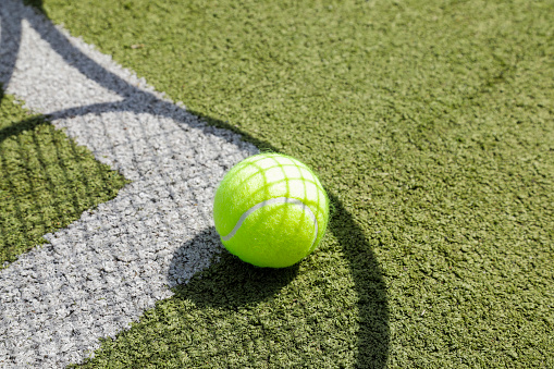 shadow of tennis racket and tennis ball on the grass tennis court with white lines, no person