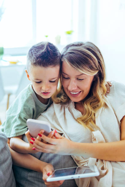 istock Mother and son at home social networking on a cell phone 1414230310