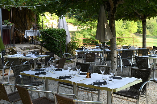 An empty outdoor restaurant terrace, a beautiful and romantic place surrounded by the nature. Seating, vintage tables and chairs served for guests.