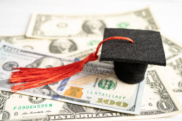 istock Graduation gap hat on US dollar banknotes money, Education study fee learning teach concept. 1414231570