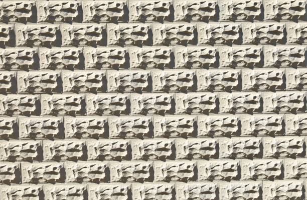 istock Gray concrete wall with decorative rectangle forms in shape of rocks carved on the surface. 1414233530
