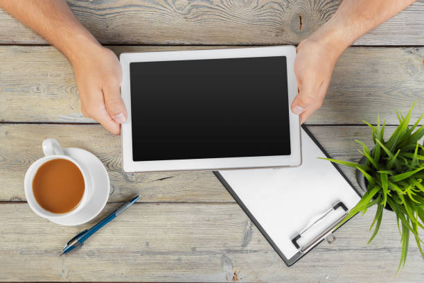 istock hands of a man holding blank tablet device over a wooden workspace table 1414233586