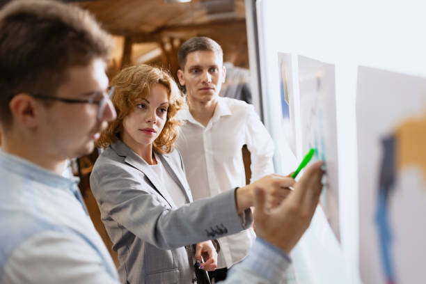istock Project presentation. Group of happy, motivated young people discussing plans and projects. Coworkers working at office, indoors. Concept of business 1414233878
