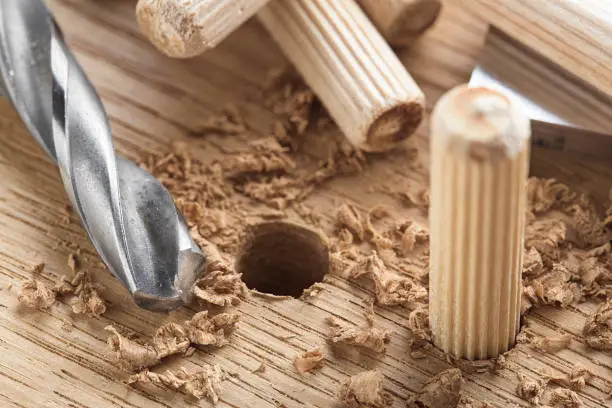 Photo of drill bit makes hole in wooden oak board for wooden dowel.