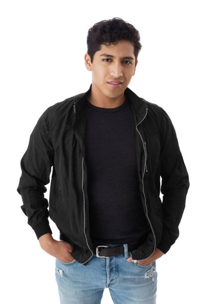 A happy young latin man standing with his hands in her pockets and smiling at the camera.