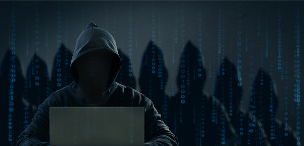 Dangerous anonymous hackers are using laptops for identity theft, internet, cybercrime. Cyber attack, destruction and malware concept. Blackout. Digital binary code on background.