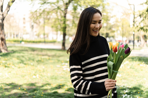 Portrait of a beautiful Asian woman with a flower bouquet walking in the park
