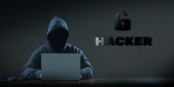 Dangerous anonymous hackers are using laptops for identity theft. with a ''hacker'' font on the back cyber crime cyber attack System destruction.
