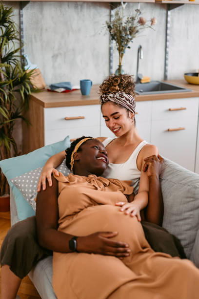 istock Pregnant Lesbian Couple Embracing Each Other On The Sofa 1414239355