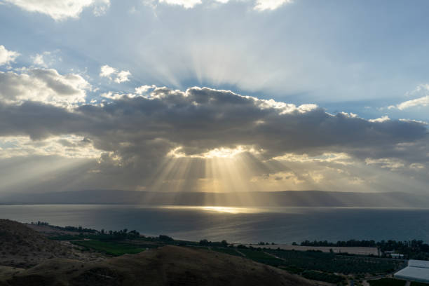 雨雲を通して海に輝く太陽の光。ガリラヤ湖, イスラエル - lake tiberius ストックフォトと画像