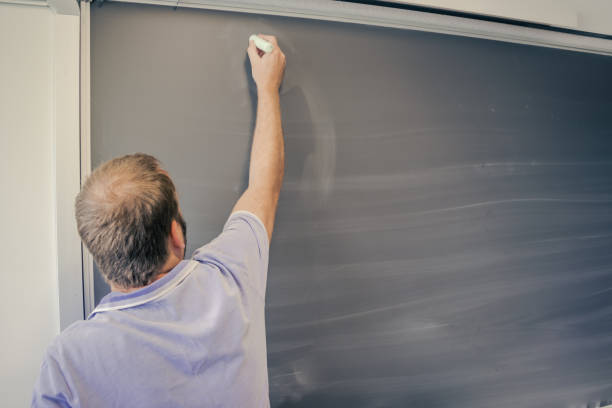 teacher writing on the blackboard in a school, back to school stock photo