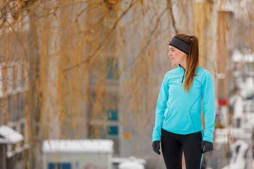 Girl wearing sportswear, city background. Winter sports, outdoor fitness, fashion, workout, health concept.