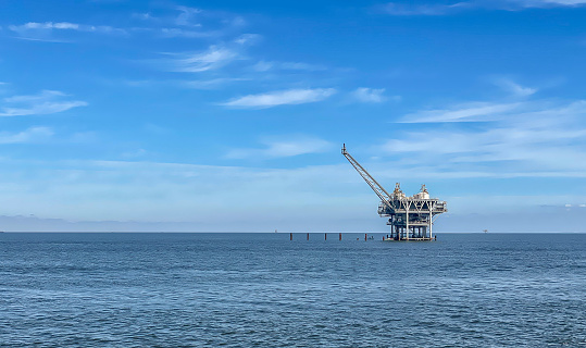 Offshore drilling platform just off shore in the Gulf of Mexico used for domestic energy production.  Ample copy space in the vibrant blue sky if needed.  Concepts could include energy production, environmental impact, others.