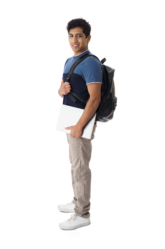 A latin Male student standing with a backpack and laptop, looking at camera and smiling.